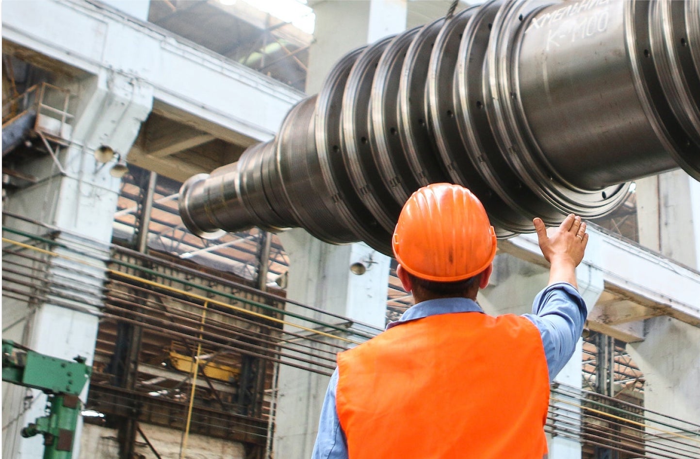 manufacturing worker directing the placement of a pipe.