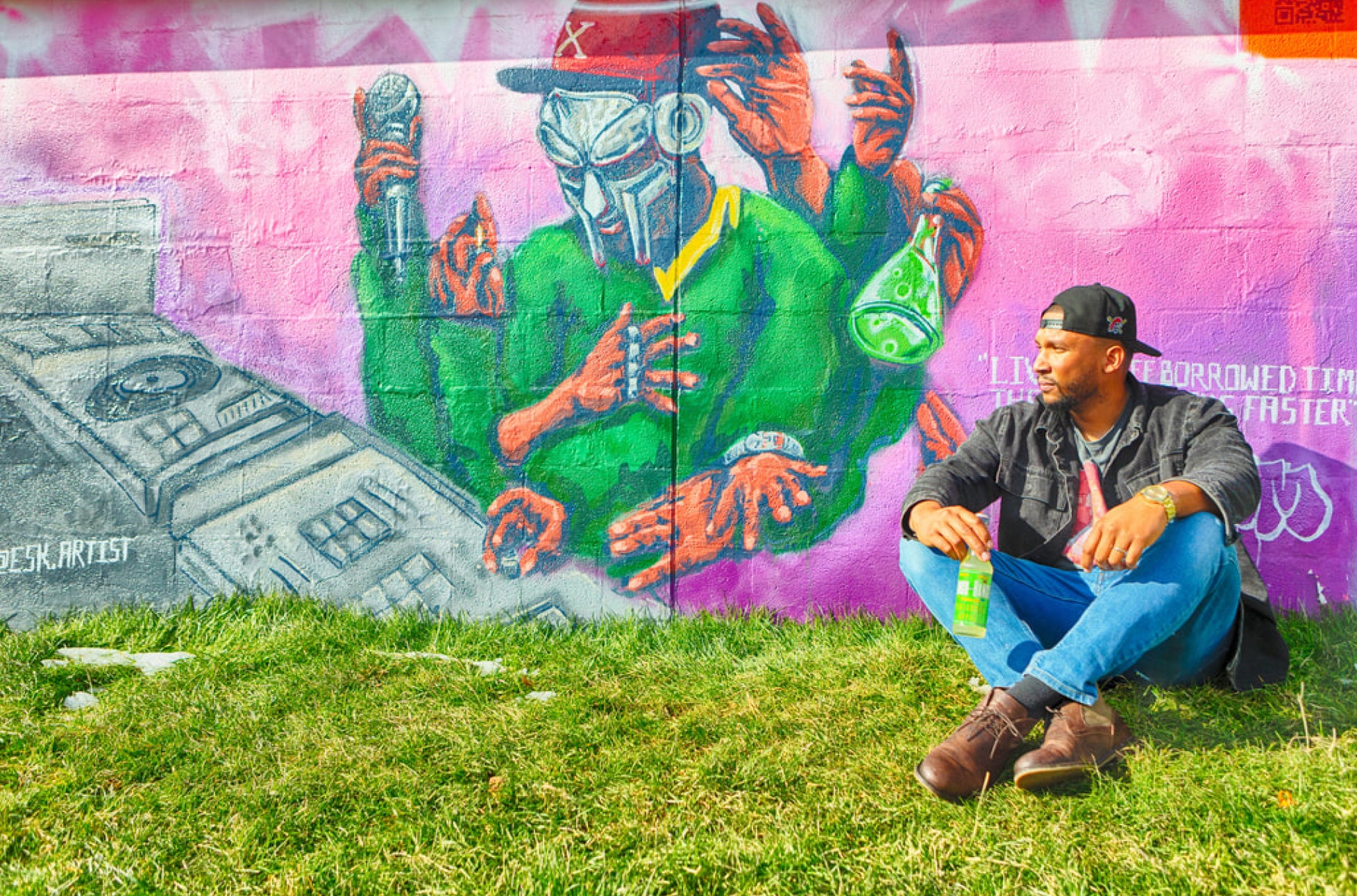 man sitting against a wall and drinking